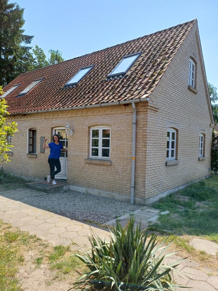 Marlies bij de voordeur van een 2-onder-1 kap woning in Denemarken.