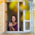 Marlies kijkt uit het raam met een glas thee in haar hand.